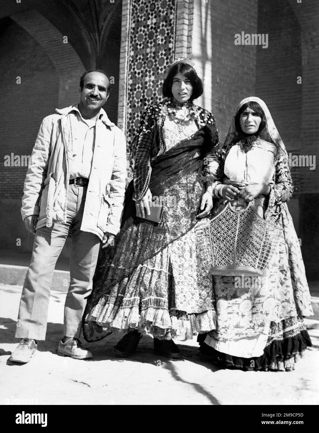 Qashqai (also Ghashghai, Kashkai, Qashqay and Qashqa'i) are Iran's largest group of nomadic pastoralist people primarily living in the provinces of Fars, Khuzestan and southern Isfahan, especially around the city of Shiraz in Fars, as depicted in this photograph. The full skirts of the women are in very bright colours and topped by gauzy veils and scarfs, often gold and silver. Stock Photo