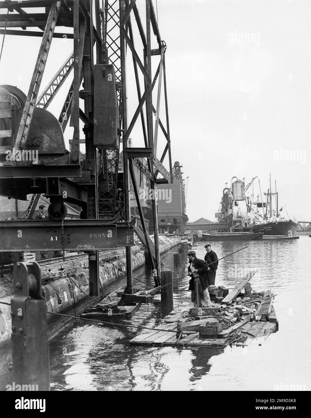 Dockside scene with men on a raft and vessels in the background, River Thames, Port of London. Stock Photo