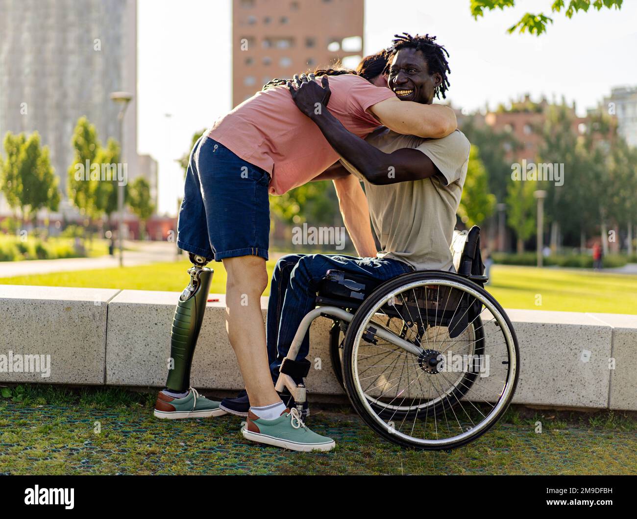 Two men with disabilities embrace in a city park, representing unity and inclusion despite ethnic differences and diversity of abilities. Image highli Stock Photo