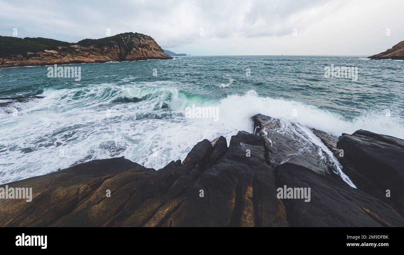 A beautiful landscape of splashing waves at the rocky shore Stock Photo ...
