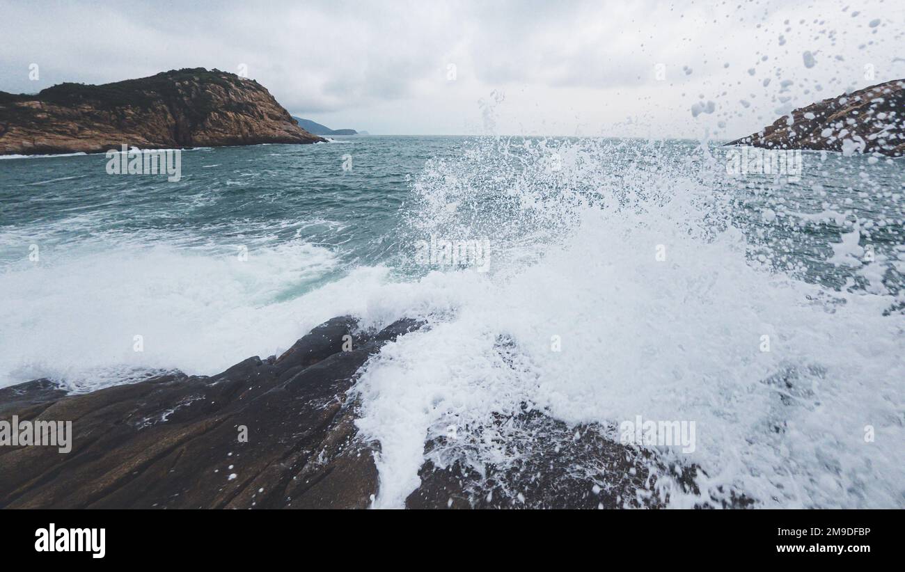 A beautiful landscape of splashing waves at the rocky shore Stock Photo ...