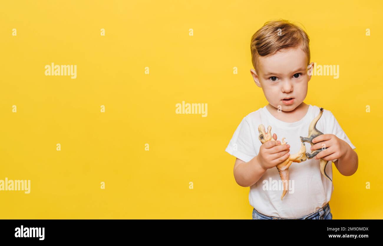 Cute laughing little boy yellow background with a dinosaur toy in his ...