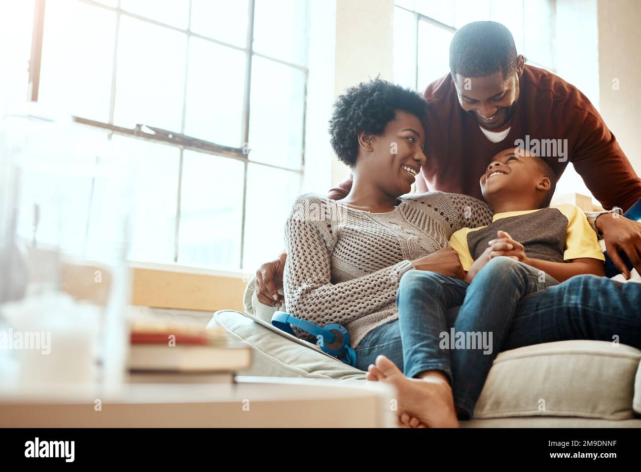 Black family, happy and relax on sofa with boy and parents, hug and laughing in their home together. Happy family, mother and father playing with Stock Photo