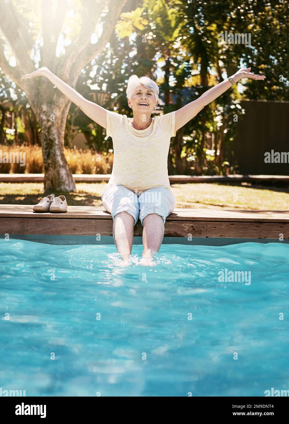 Senior woman, smile and feet in swimming pool in relax for summer vacation, swim or holiday joy in the outdoors. Happy elderly female with arms Stock Photo