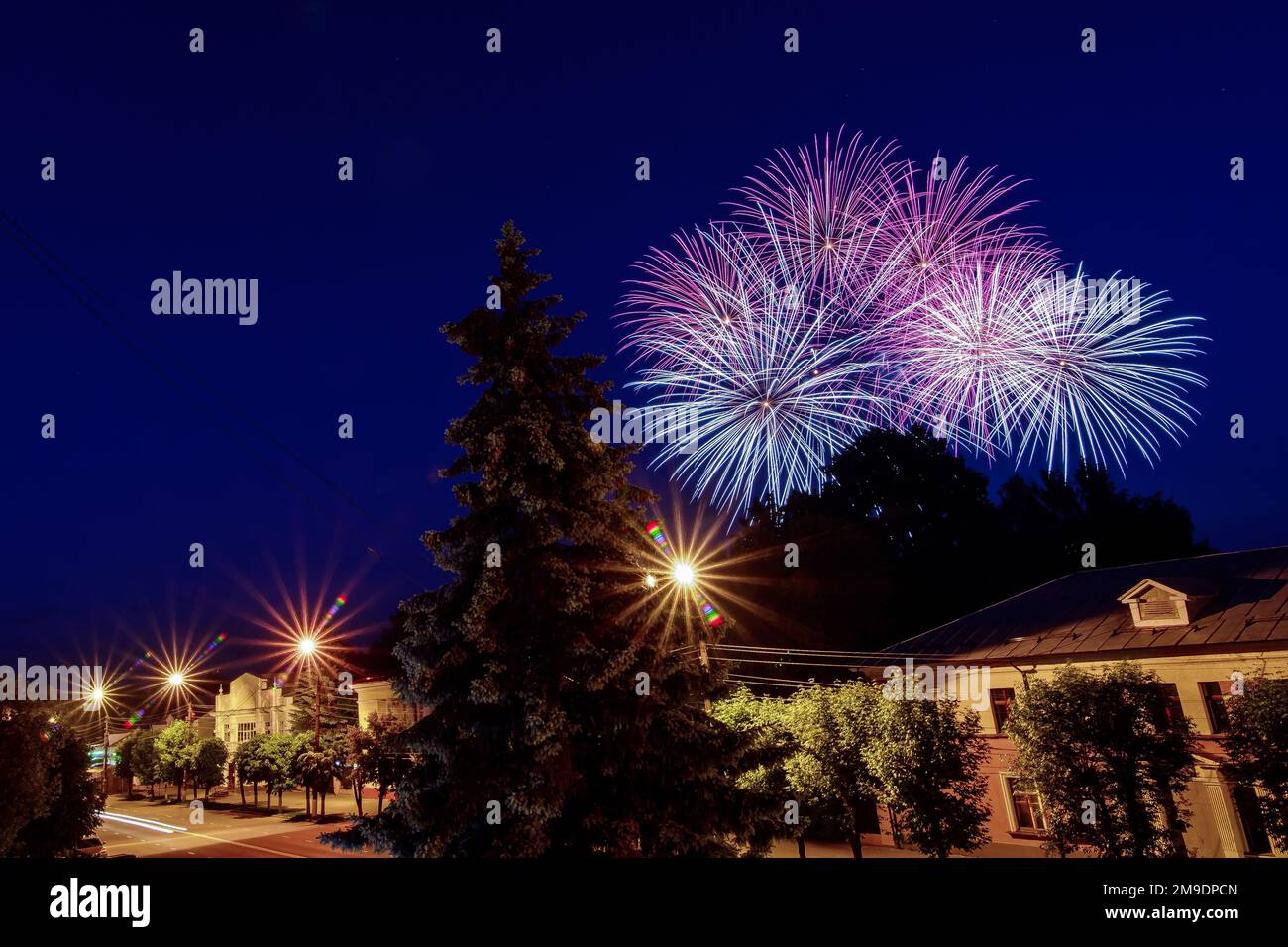 Multicolored fireworks on the holiday over the city against the night blue sky Stock Photo