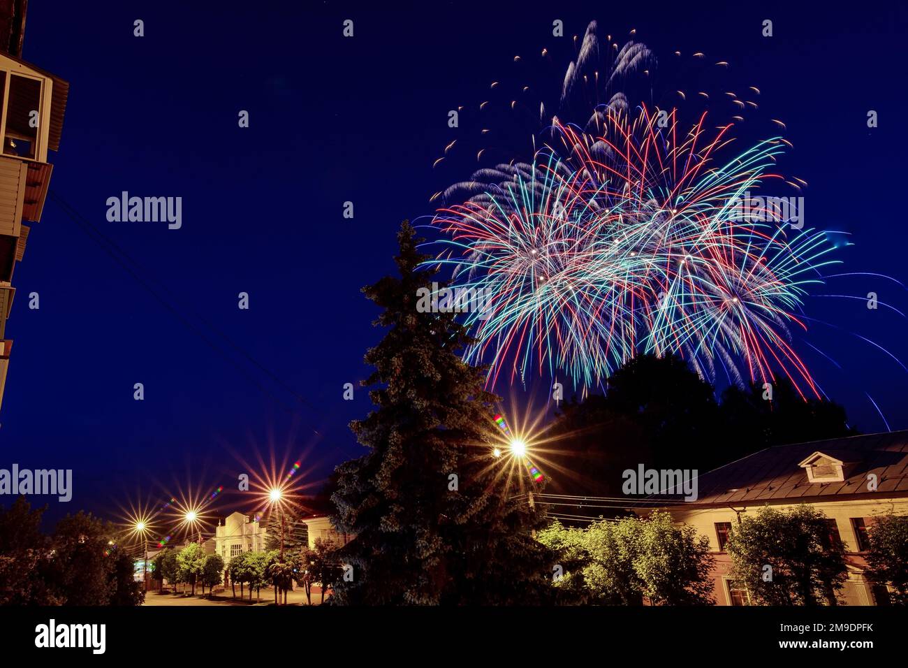 Multicolored fireworks on the holiday over the city against the night blue sky Stock Photo