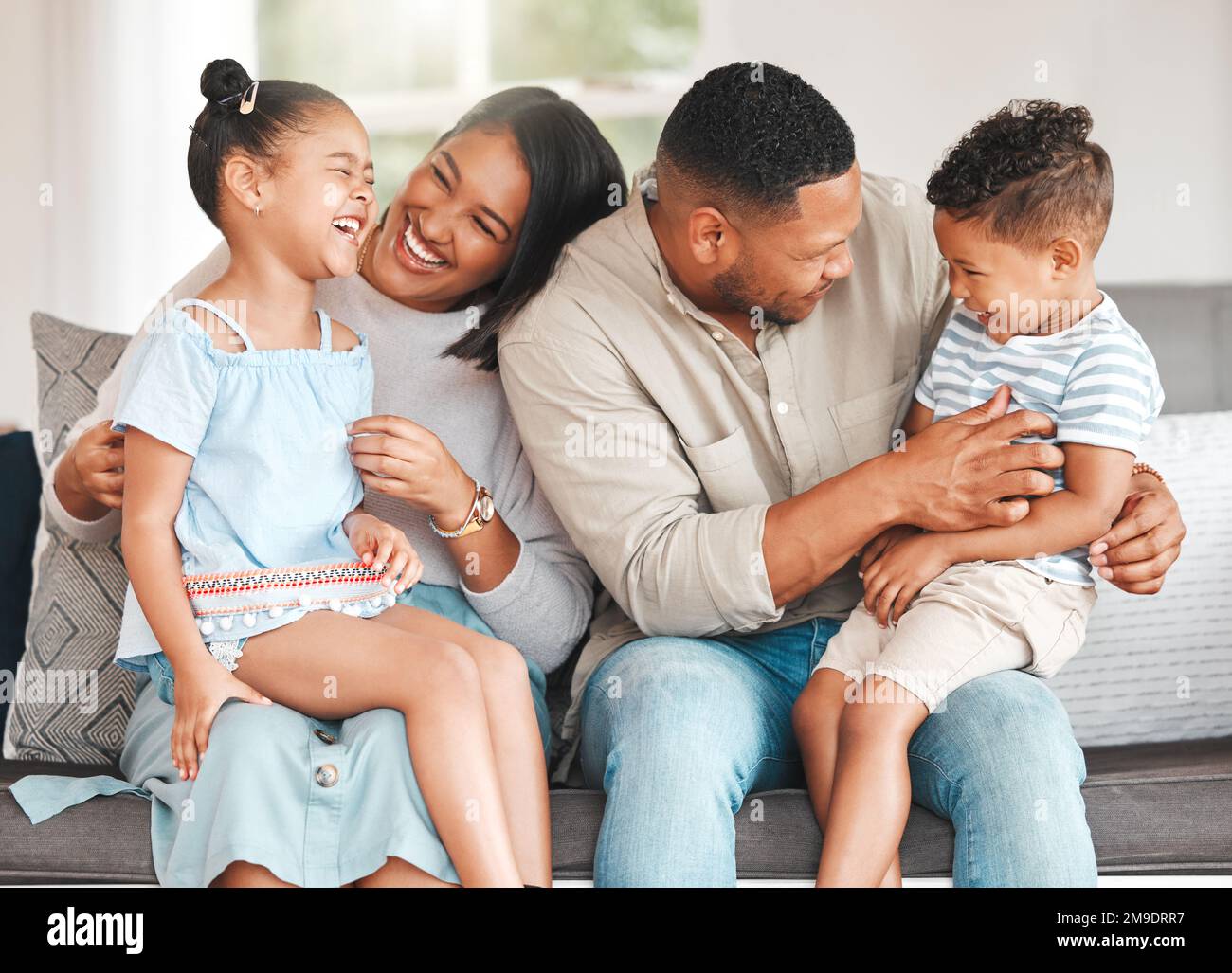 Fun with giggles. a young family playing together on a sofa at home. Stock Photo