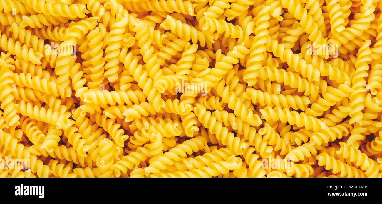 Raw dry fusilli pasta, food background texture, top view horizontal