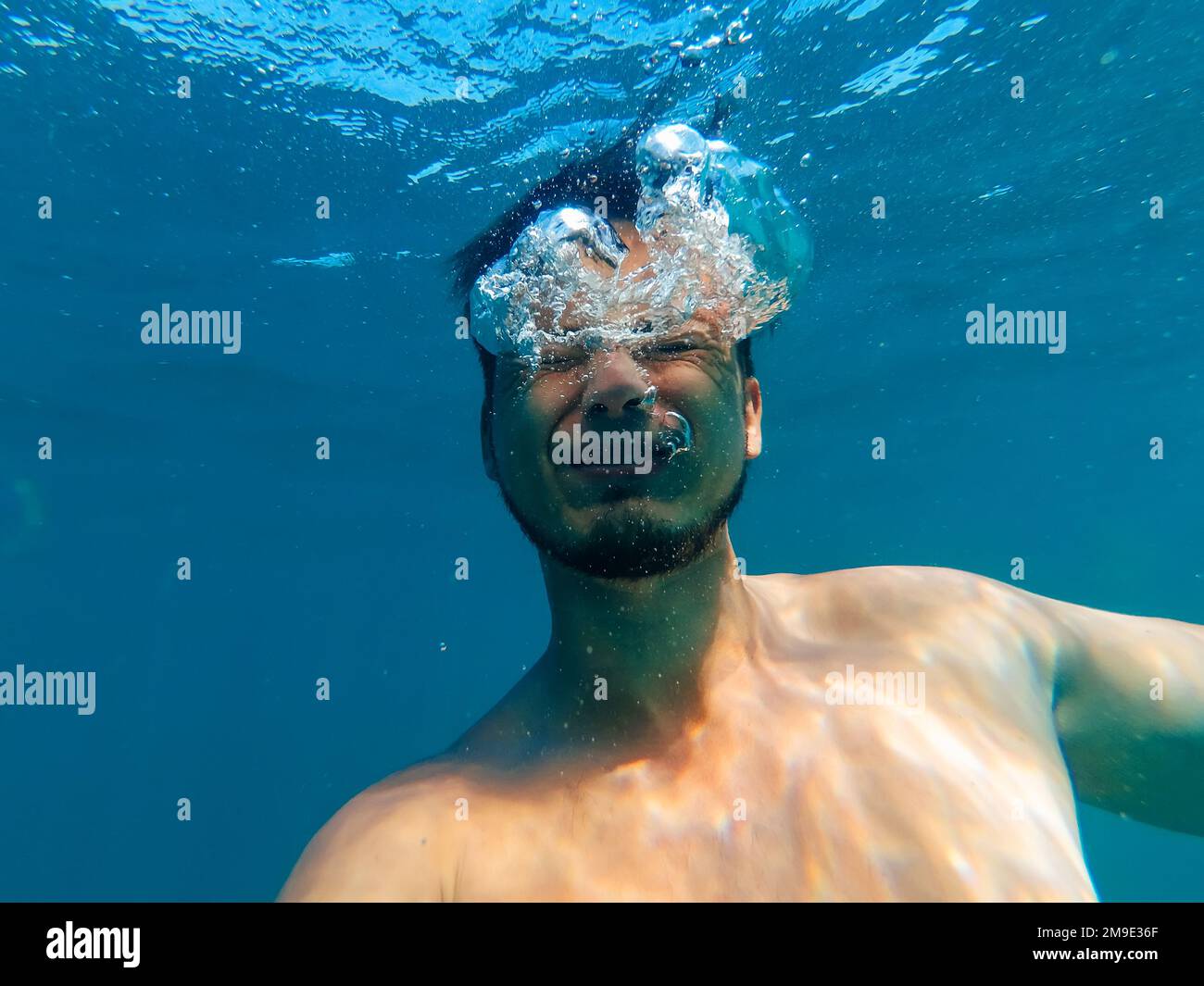 man is drowning in a deep blue sea under the water with an expression