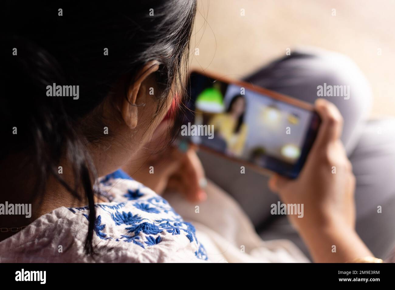 An Indian woman with smart phone enjoying online content at home Stock Photo