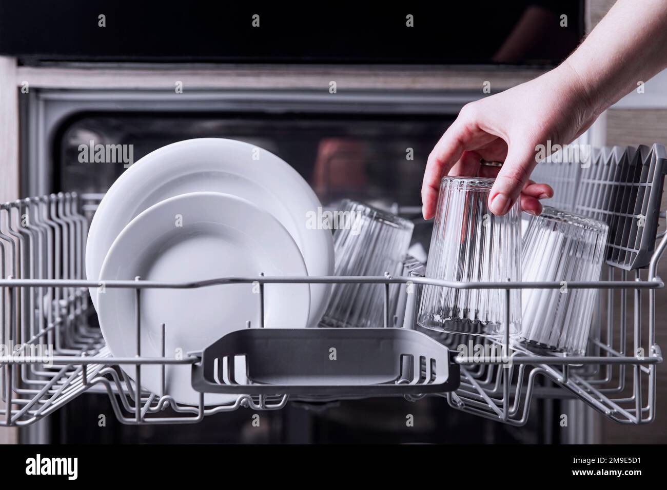 Female Hand Loading Dished Empty Out Or Unloading Dishwasher With