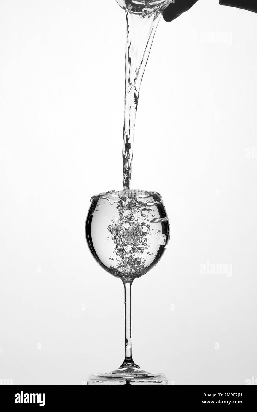 Backlight shot Pouring water into glass, white background Stock Photo