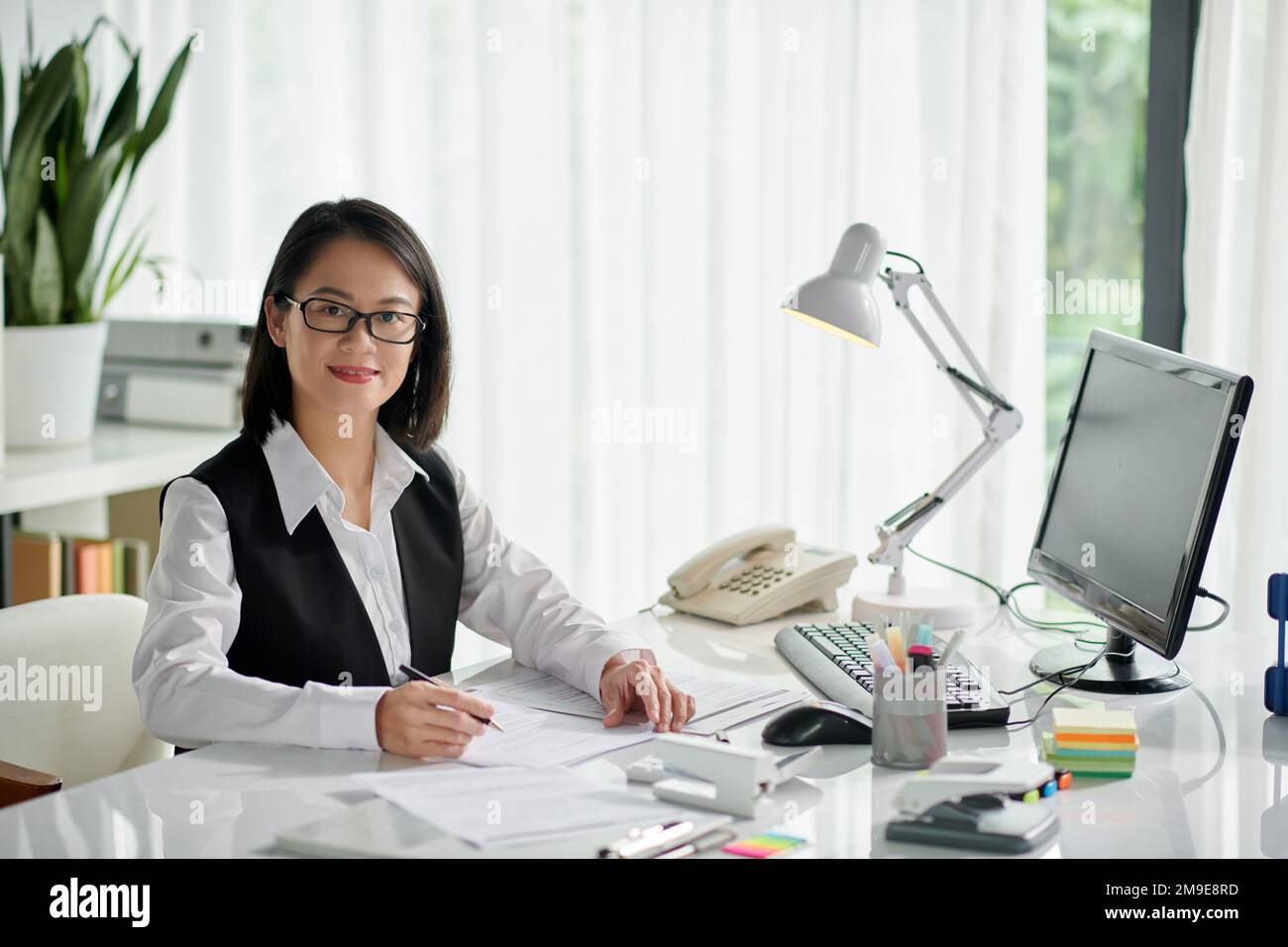 Smiling social consultant working with documents of client at office ...