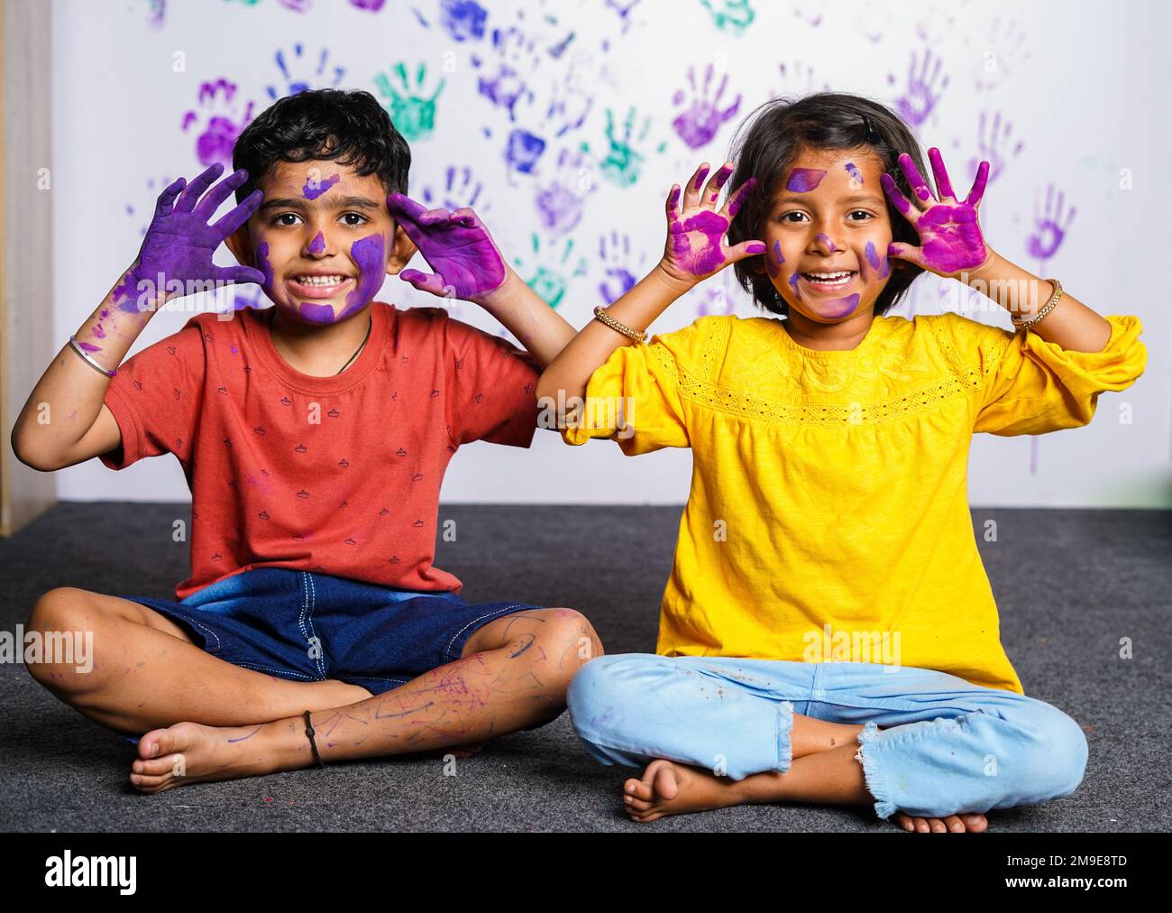 Cheerful kids with messy colorful hands grimacing to camera at home - concept of mischievous, innocent and humor. Stock Photo