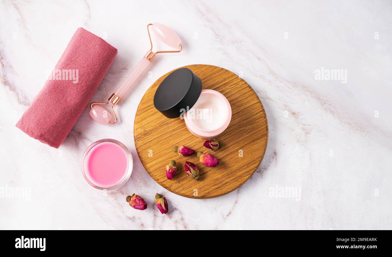Face cream, soap and massager on a marble table. The concept of care cosmetics with rose. Health and beauty. Top view and copy space. Stock Photo