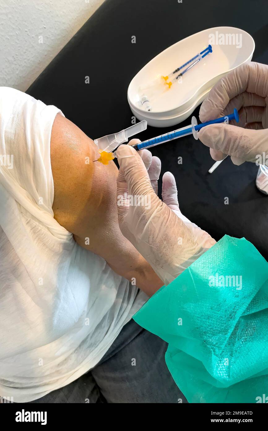 Elderly woman receives injection with medical syringe fourth vaccination booster vaccination against coronavirus disease Covid-19 C19 corona virus Stock Photo