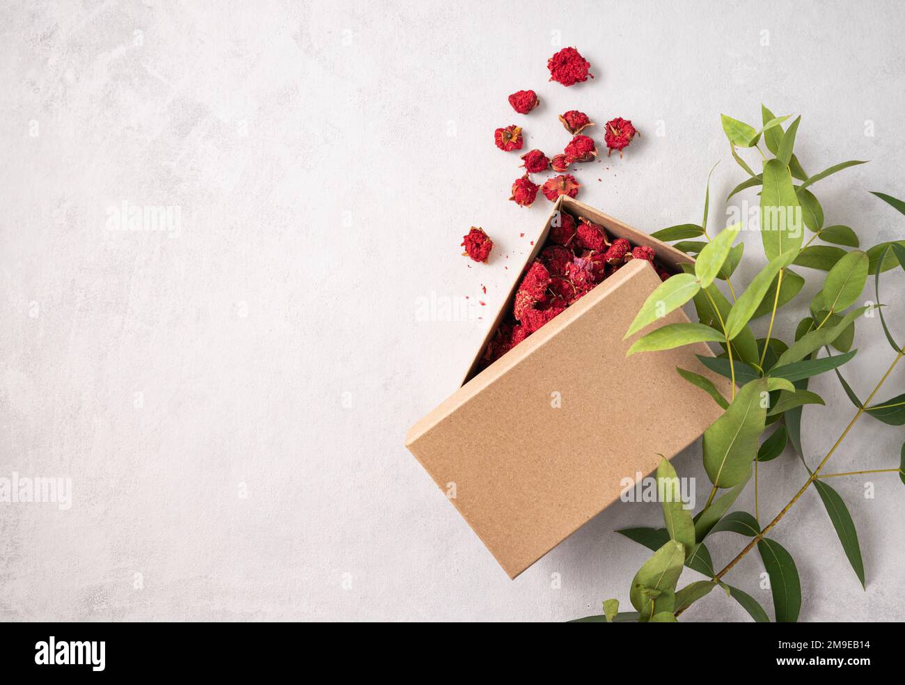Craft box with red dry flowers on a gray textured background with branch plant. The concept of ecological packaging and zero waste. Mock up, copy spac Stock Photo