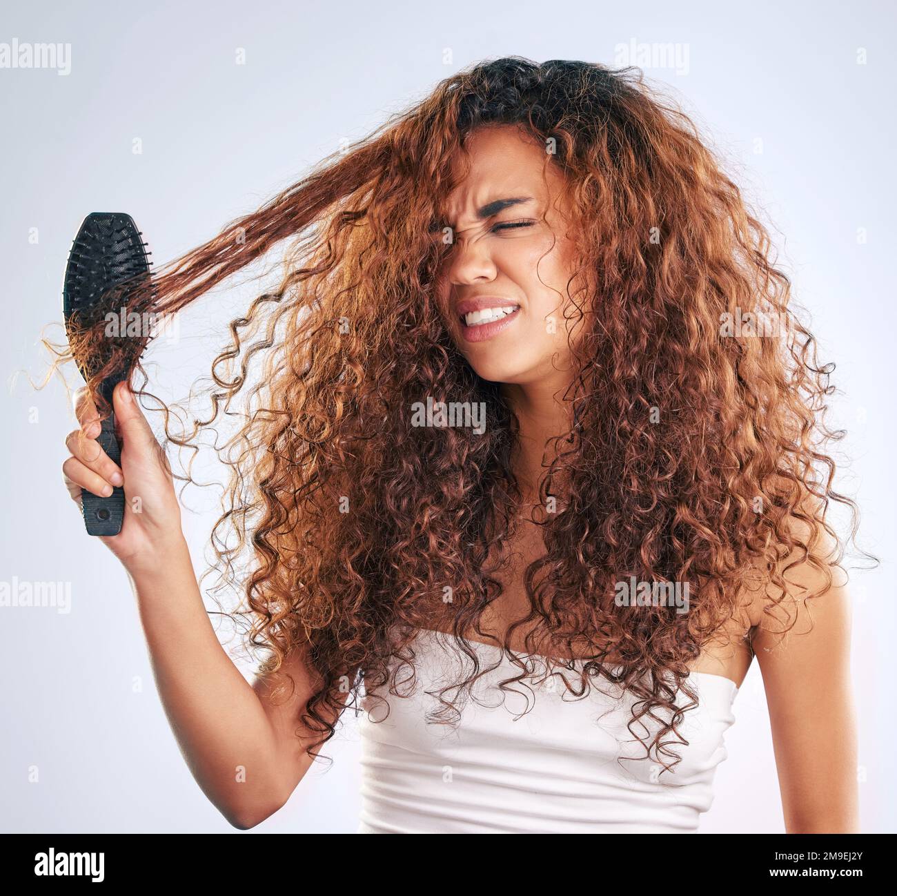 Knot today. an attractive young woman struggling with knotted hair in