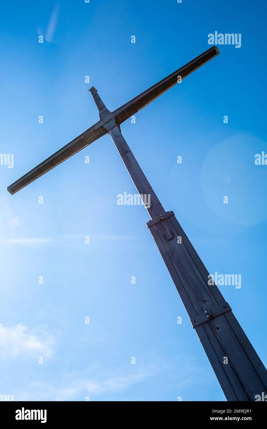 A vertical low angle shot of a big wooden cross against a blue sky ...