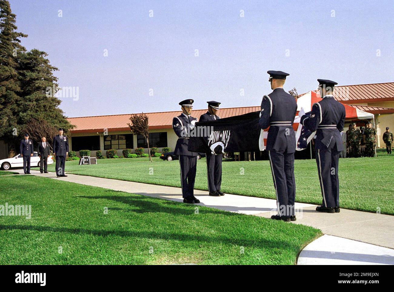 Medium long shot, the Travis Air Force Base, California, Elite Honor Guard perform a double flag folding ceremony during a special retreat ceremony held on 17 September 1999, honoring all POW/MIAs. Brigadier General Steven A. Roser, USAF, Commander 60th Air Mobility Wing, Travis AFB, and Major Robert Brubaker (U.S. Air Force Retired) are in left background. Not shown - BG Roser presented MAJ Brubaker with the Purple Heart. Base: Travis Air Force Base State: California (CA) Country: United States Of America (USA) Stock Photo
