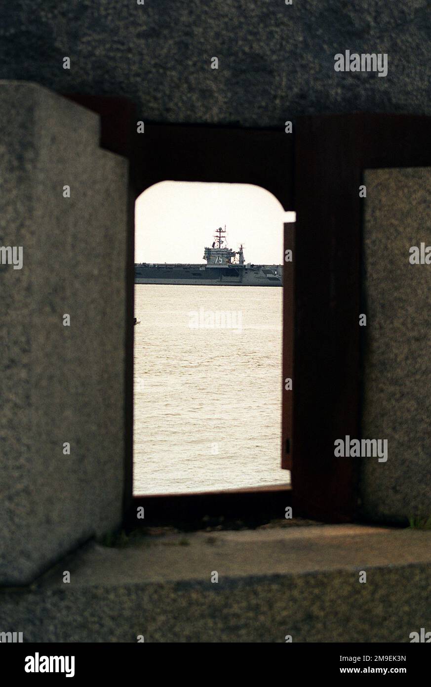 A view of the amidships section of the Nuclear-Powered Aircraft Carrier USS HARRY S. TRUMAN (CVN 75) through one of the gun ports of the old coastal defense battery at Fort Wool on the entrance into the inner harbor. Base: Hampton Roads, Norfolk State: Virginia (VA) Country: United States Of America (USA) Stock Photo