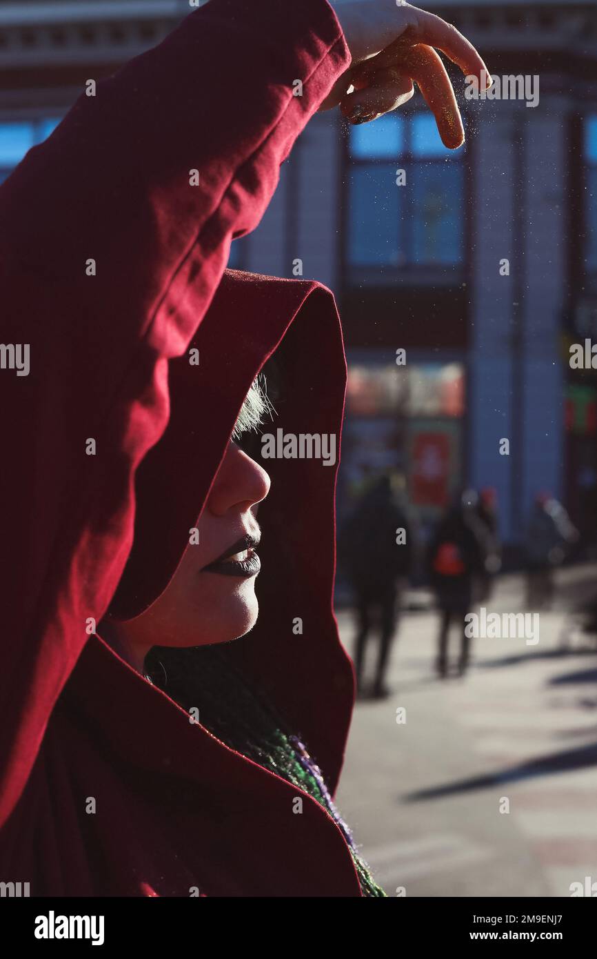 Close up fantasy woman in red hood sprinkling pixie dust above head portrait picture Stock Photo