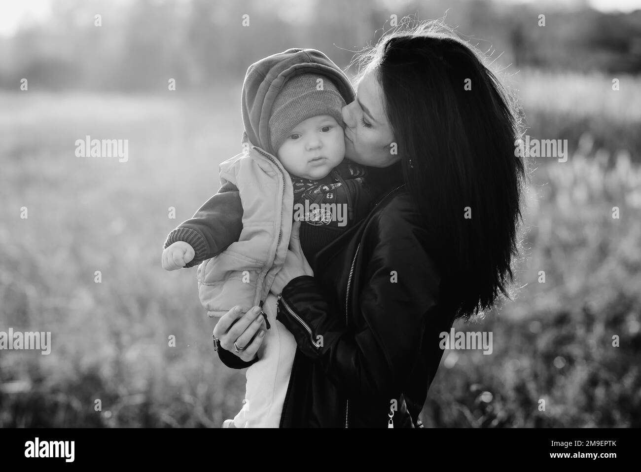 Young mother kissing her little baby boy son on nature Stock Photo