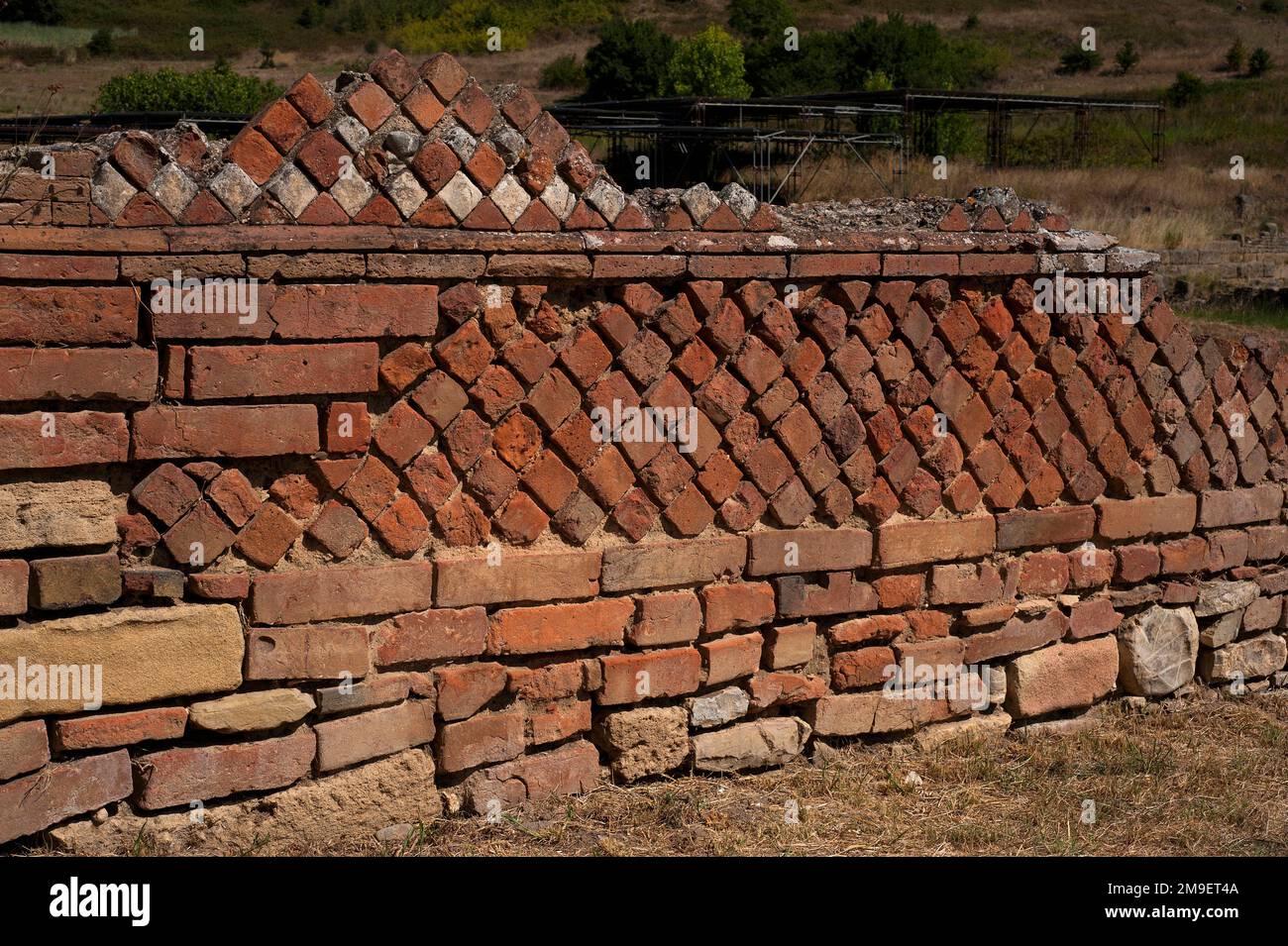 Opus reticulatum and Opus mixtum, two ancient Roman construction techniques combined in a wall at the Graeco-Roman seaport of Velia, Campania, Italy. Opus reticulatum, introduced by the late 2nd century BC, was a method of facing a wall with square or pyramid-shaped blocks of stone or brick set in a diagonal grid.  In Opus mixtum, introduced in the 1st and 2nd centuries AD, panels of opus reticulatum were separated by bands of brick facing, which probably saved on manpower and on bricks.  The resulting strip design is common in buildings of the Late Roman Empire. Stock Photo