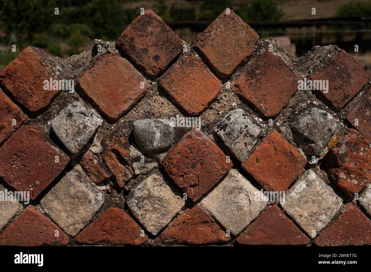 Close detail view of Opus reticulatum, decorative ancient Roman walling using blocks of stone, brick or tuff laid in diagonal grid patterns.  Top of ruined wall in southern district of Velia, a Greco-Roman seaport on southern Italy’s Tyrrhenian Sea coast at Marina di Ascea, Campania. Stock Photo
