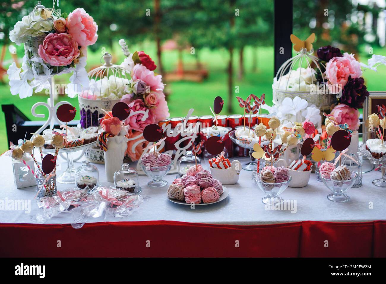 pink and white candy bar with marshmallows and cupcakes decorated with