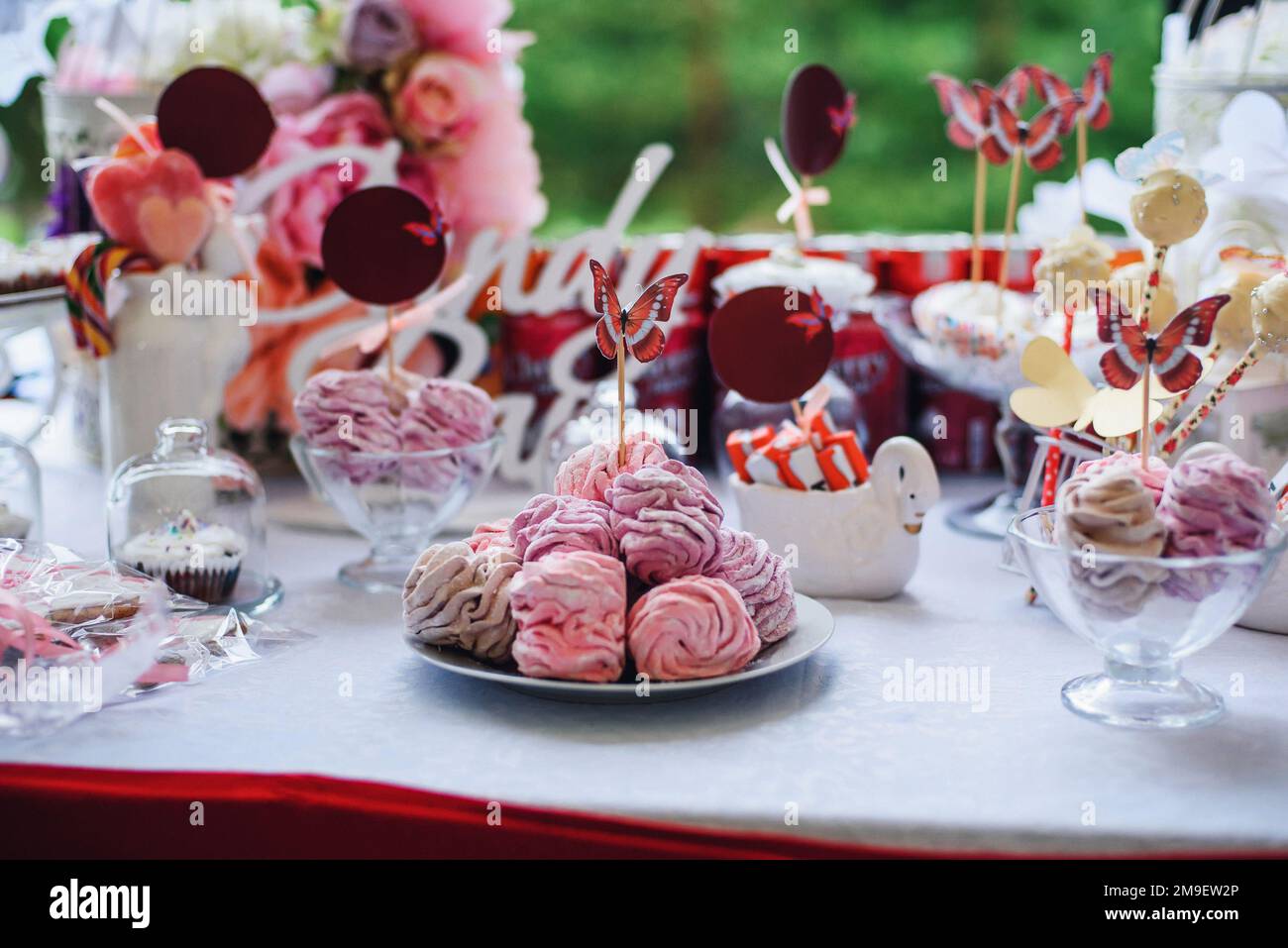 pink and white candy bar with marshmallows and cupcakes decorated with