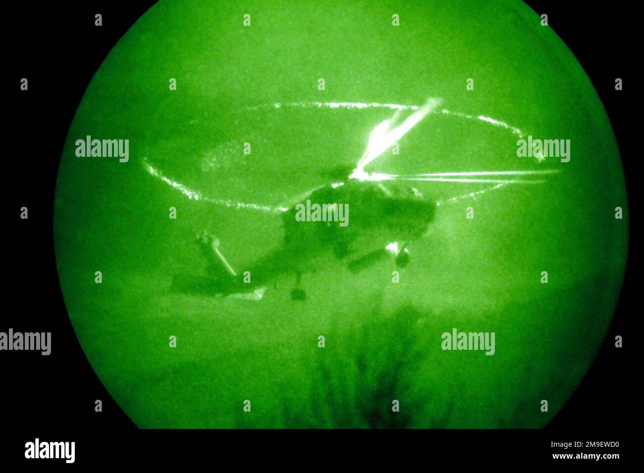 Right side front view, medium shot from a low angle at nighttime, through a Starlight System as a US Navy HH-60 from Helicopter Anti-Submarine Squadron Wing Pacific stationed at NAS North Island, Coronado, California, emits laser range identifier while providing cover support for simulated rescue operations. Desert Rescue is a Joint Service Combat Search and Rescue (CSAR) exercise designed to fully integrate planning and execution of both immediate and dedicated missions. Subject Operation/Series: DESERT RESCUE Base: Naval Air Station, Fallon State: Nevada (NV) Country: United States Of Americ Stock Photo