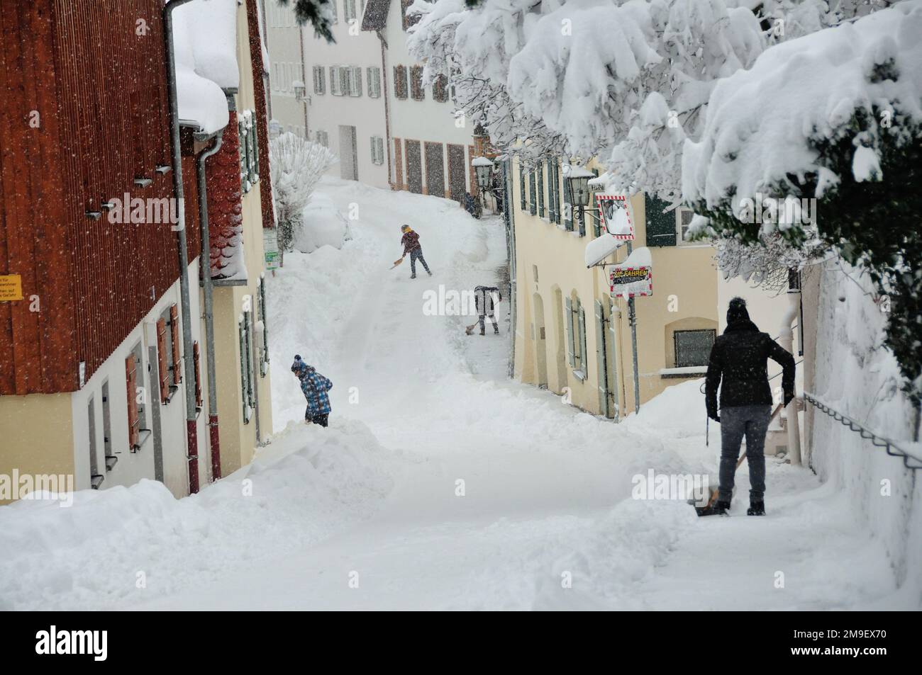 Snow shovelling on streets in an alpine village Stock Photo