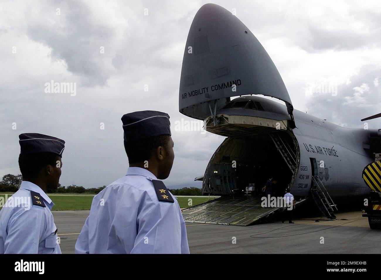 Members of the South African Air Force watch as a C-5 Galaxy transport aircraft from 436th Airlift Wing, at Dover Air Force Base, Delaware, delivers cargo pallets, personnel, and two HH-60 Blackhawk helicopters (Aircraft's cargo not shown) from the 41st Rescue Squadron at Moody Air Force Base, Georgia, to Hoedspruit Air Force Base, South Africa, on Mar. 7, 2000, during 'Operation Atlas Response.' The personnel and helicopters are the first American HH-60's delivered to aid in the distribution of relief supplies and rescue stranded flood victims (Not shown) in Mozambique. Subject Operation/Seri Stock Photo