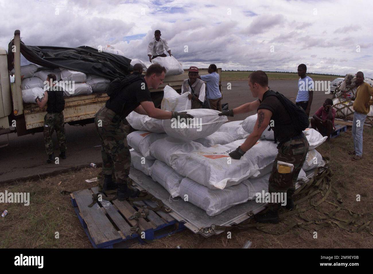 Medium long shot. STAFF Sergeant Manfred Browder, and SENIOR AIRMAN Shane Redding, both Air Transportation Specialists and members of the 86th Air Mobility Squadron, Ramstein Air Base, Germany, with help of local laborers, build pallets of humanitarian supplies at the International Airport at Maputo, Mozambique, Africa 17 March 2000. They and their team are deployed in support of Operation Atlas Response, a Humanitarian Aid Operation to help the people of Mozambique, after severe flooding displaced over a million people from their homes. Medium long shot.  Staff Sergeant Manfred Browder, and S Stock Photo