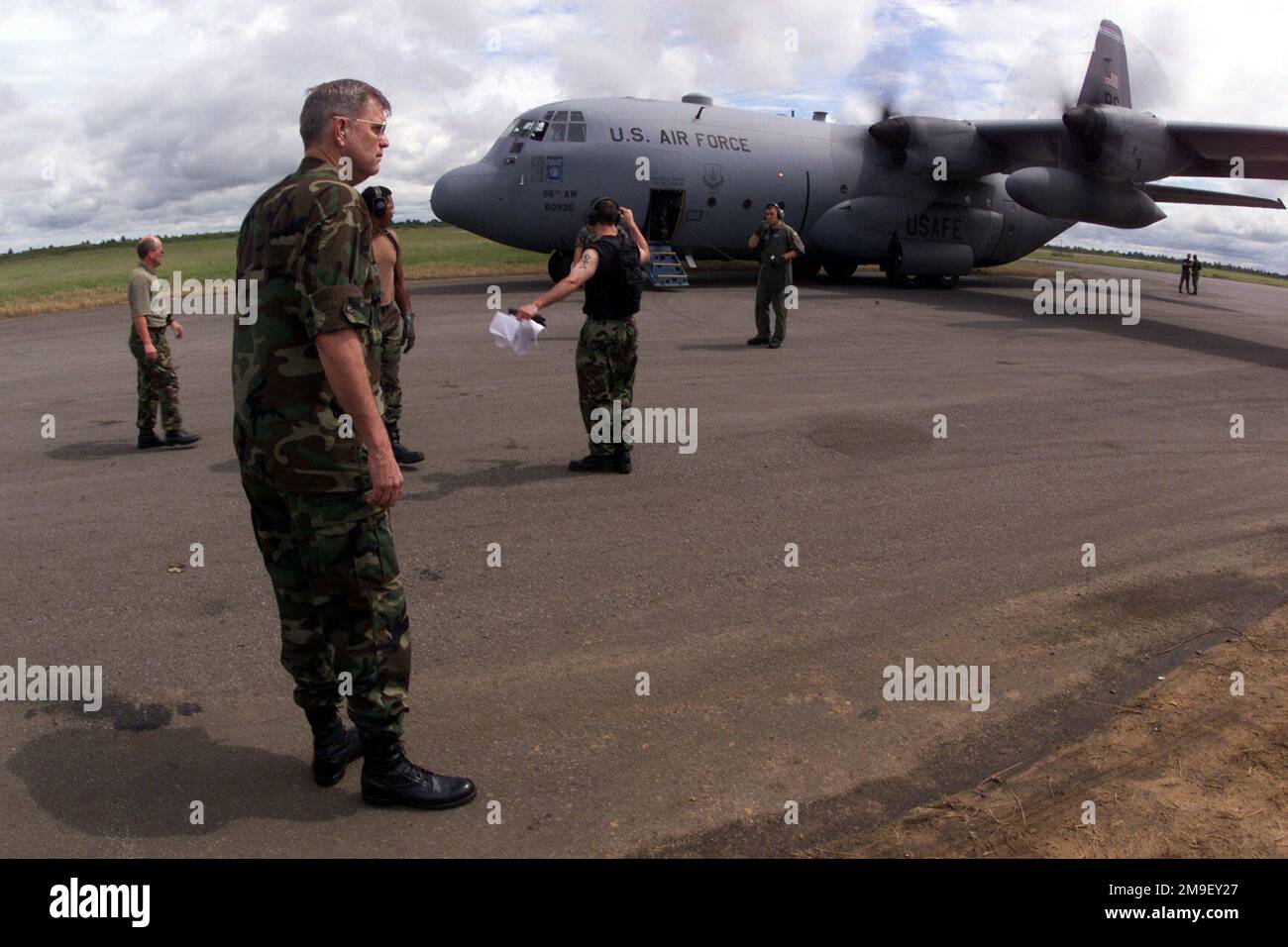 Medium shot. Major General Joe Wehrle, Joint Task Force Commander of Operation Atlas Response, 3rd Air Force Commander, Royal Air Force, Mildenhall, surveys the scenes at the International Airport in Maputo, Mozambique where a good portion of the relief airlift missions are originating, as a C-130 from the 37th Airlift Squadron, Ramstein Air Base, taxis in to be loaded with humanitiarian relief supplies on 17 March 2000. Operation Atlas Response, is a Humanitarian Aid Operation to help the people of Mozambique, after severe flooding displaced over a million people from their homes. Subject Ope Stock Photo