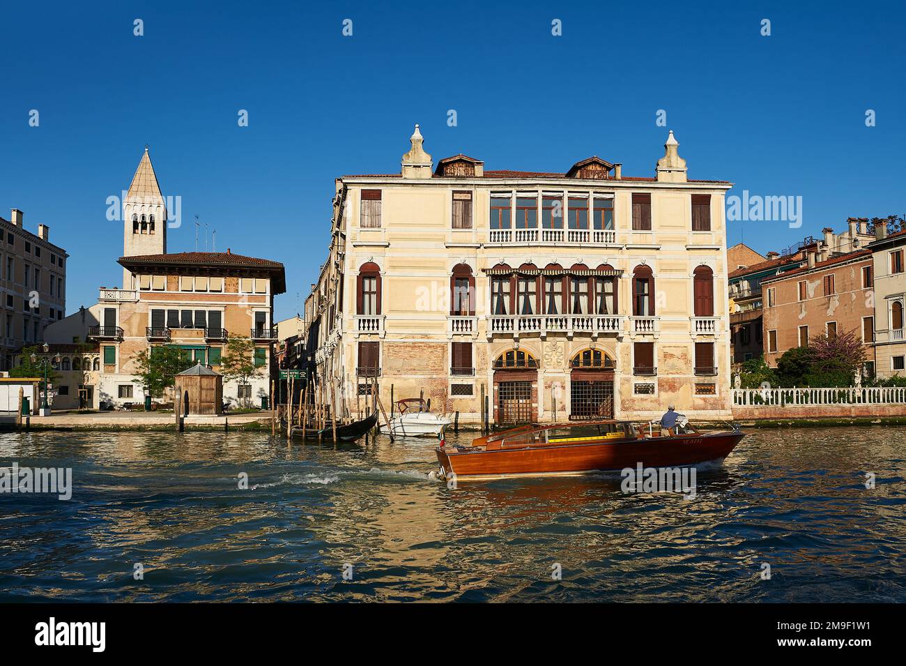 View of a typical taxi water in front of the ancient Venetian facade with its façade damaged by the effect of water and a wooden pier for small boats Stock Photo