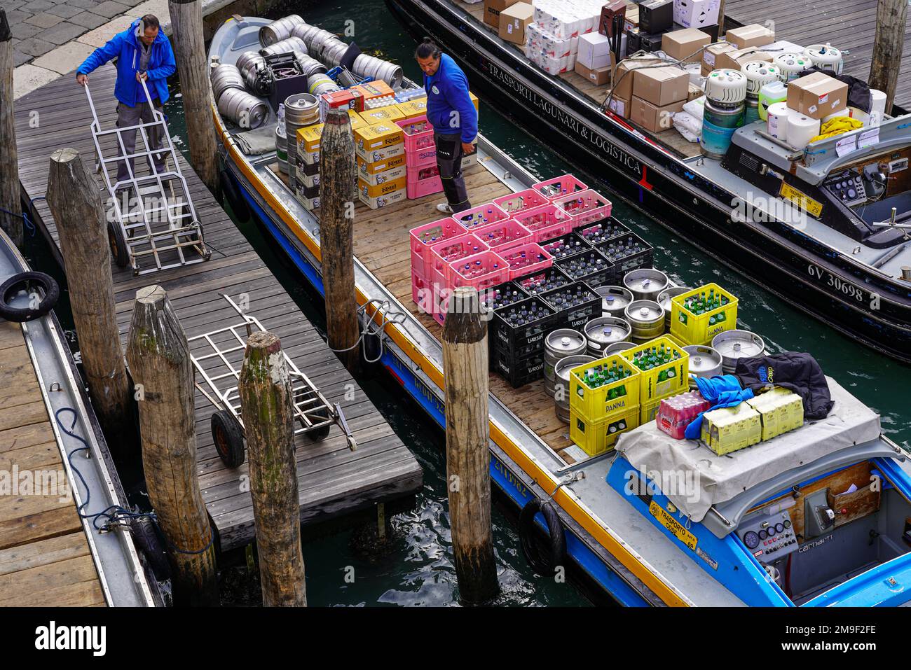 Boats of a beverage wholesaler have arrived at a trader on a canal in Venice. Barrels and bottled drinks are being delivered. Stock Photo