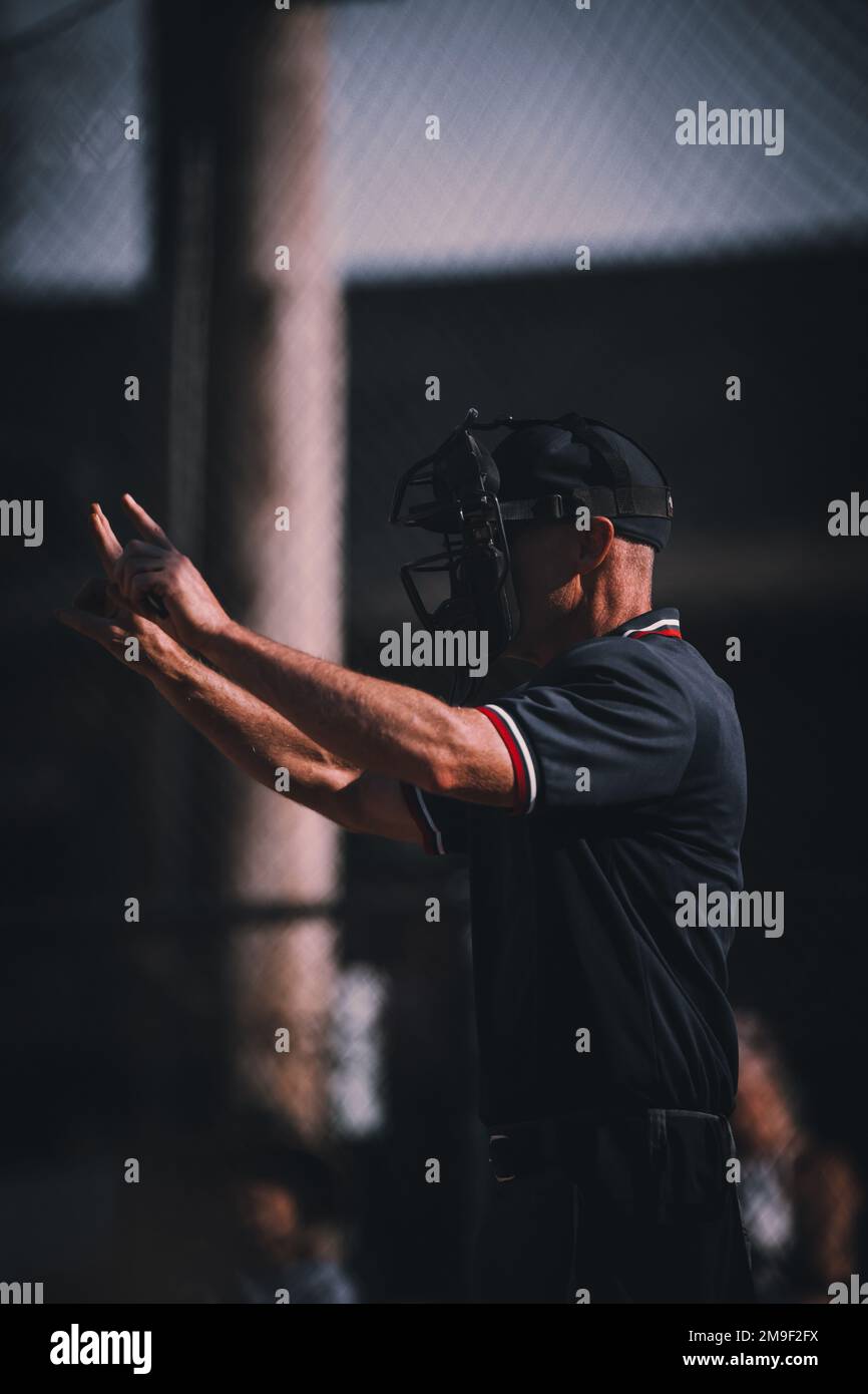 A vertical closeup of an umpire calling ball and strikes with head