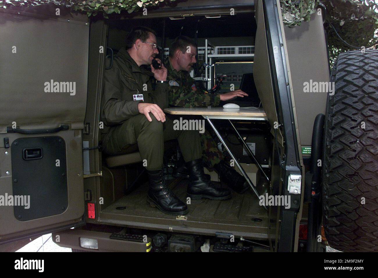 000522-F-4884R-009. [Complete] Scene Caption: CHIEF Warrant Officer (CWO) Helmut Gschwandter, (foreground), switch operator, Austrian army, works with Captain (CAPT) Urs Walther, Switch System Project Manager, performing software configurations to use in the Phase 3 test of COMBINED ENDEAVOR (CE) 2000, held at Lager Aulenbach, Germany. CE 2000, currently hosted by Germany, is the largest information and communication systems exercise in the world. This exercise is the sixth in a series of multinational communication interoperability workshops where military personnel from 35 nations get togeth Stock Photo