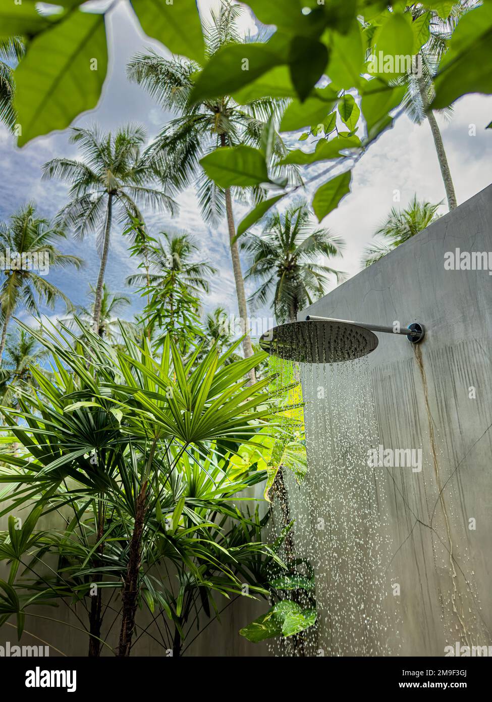 Water falling from a rain shower head in an outdoor shower setting Stock Photo