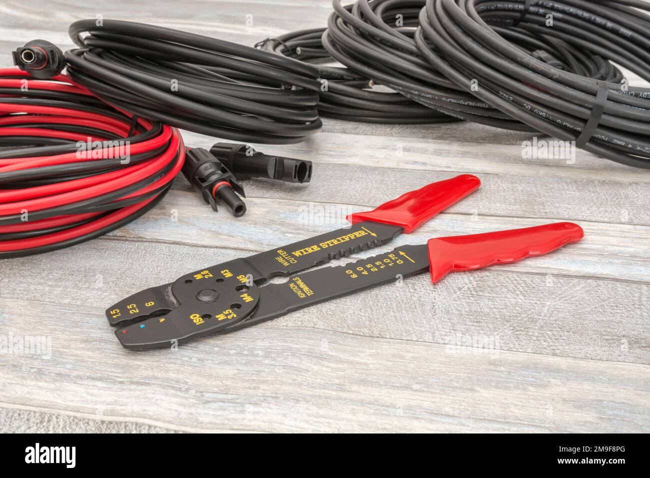 Workbench shot of Chinese made unbranded wire stripper & wire cutter for 26-10AWG wire (see Notes) with coiled Solar connector cables & MC4 sockets. Stock Photo