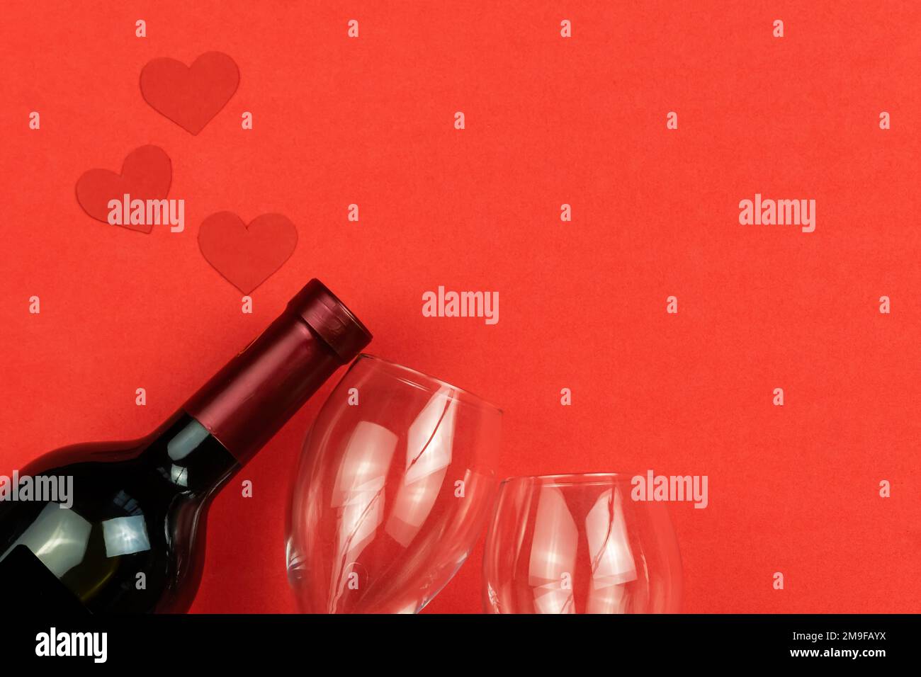 Bottle of wine, glasses hearts on a red background with copy space, top ...