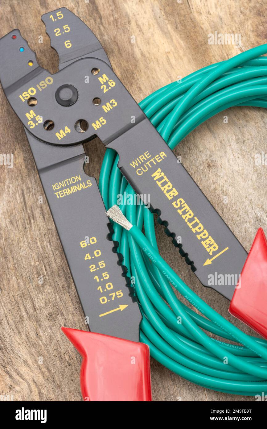 Close shot of Chinese made unbranded wire stripper & wire cutter for 26-10AWG wire (see Notes) with coiled role of green silicone covered wire. Stock Photo