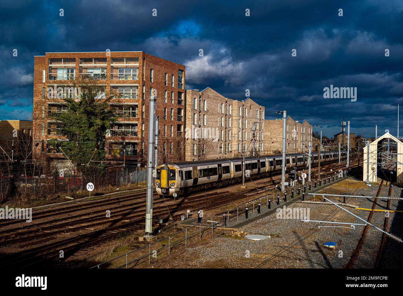 Great Northern train arrives at Cambridge Railway Station passing new build housing in the brownfield Cambridge Ironworks developmen. Stock Photo
