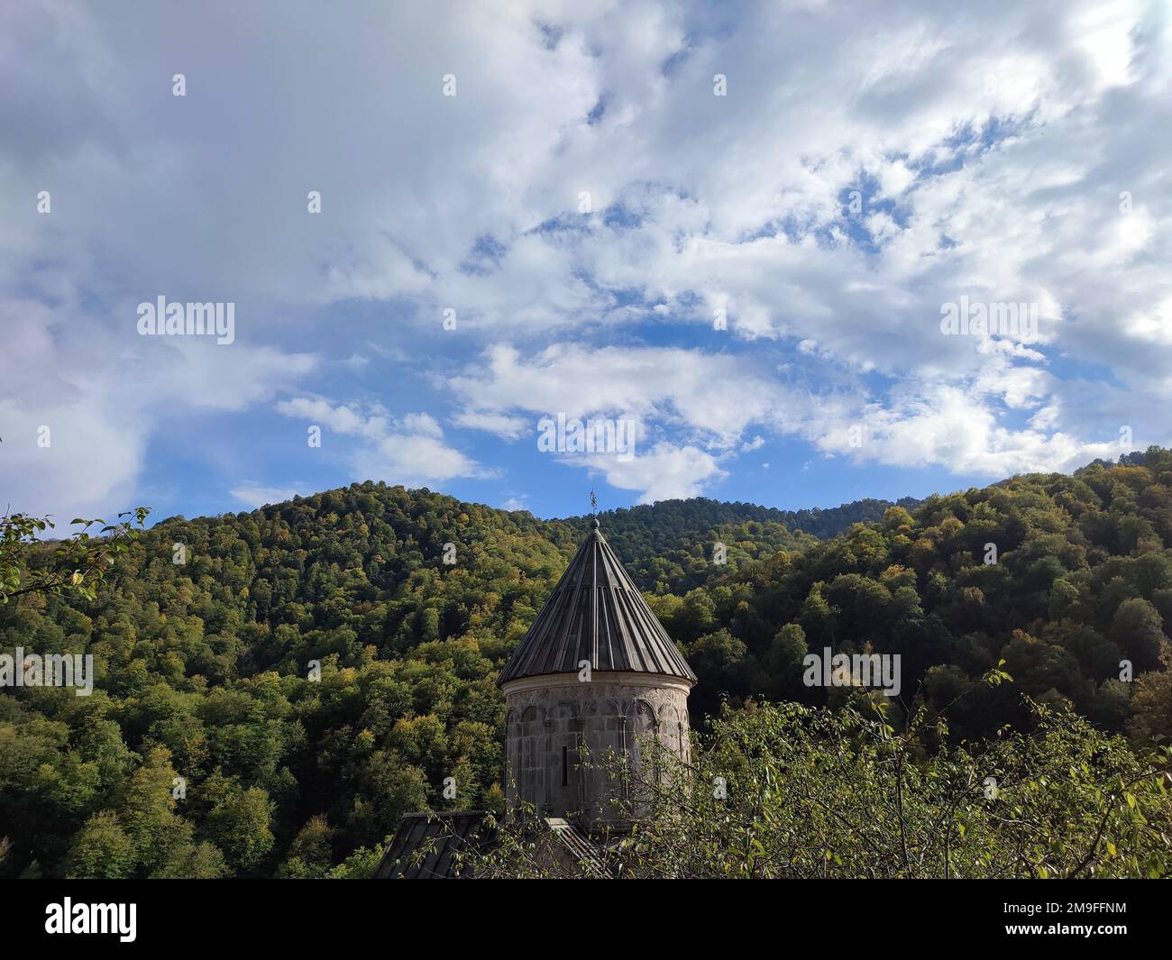 A scenic shot of the dome of the Haghartsin Monastery in Tavush, Armenia, seen behind lush trees Stock Photo