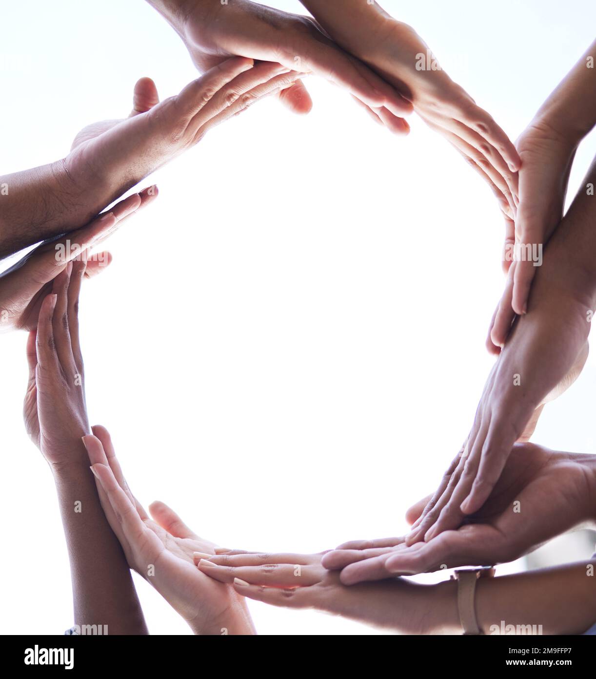 We all contribute to growth. Low angle shot of an unrecognisable group of businesspeople standing and forming a circle with their hands in the middle. Stock Photo