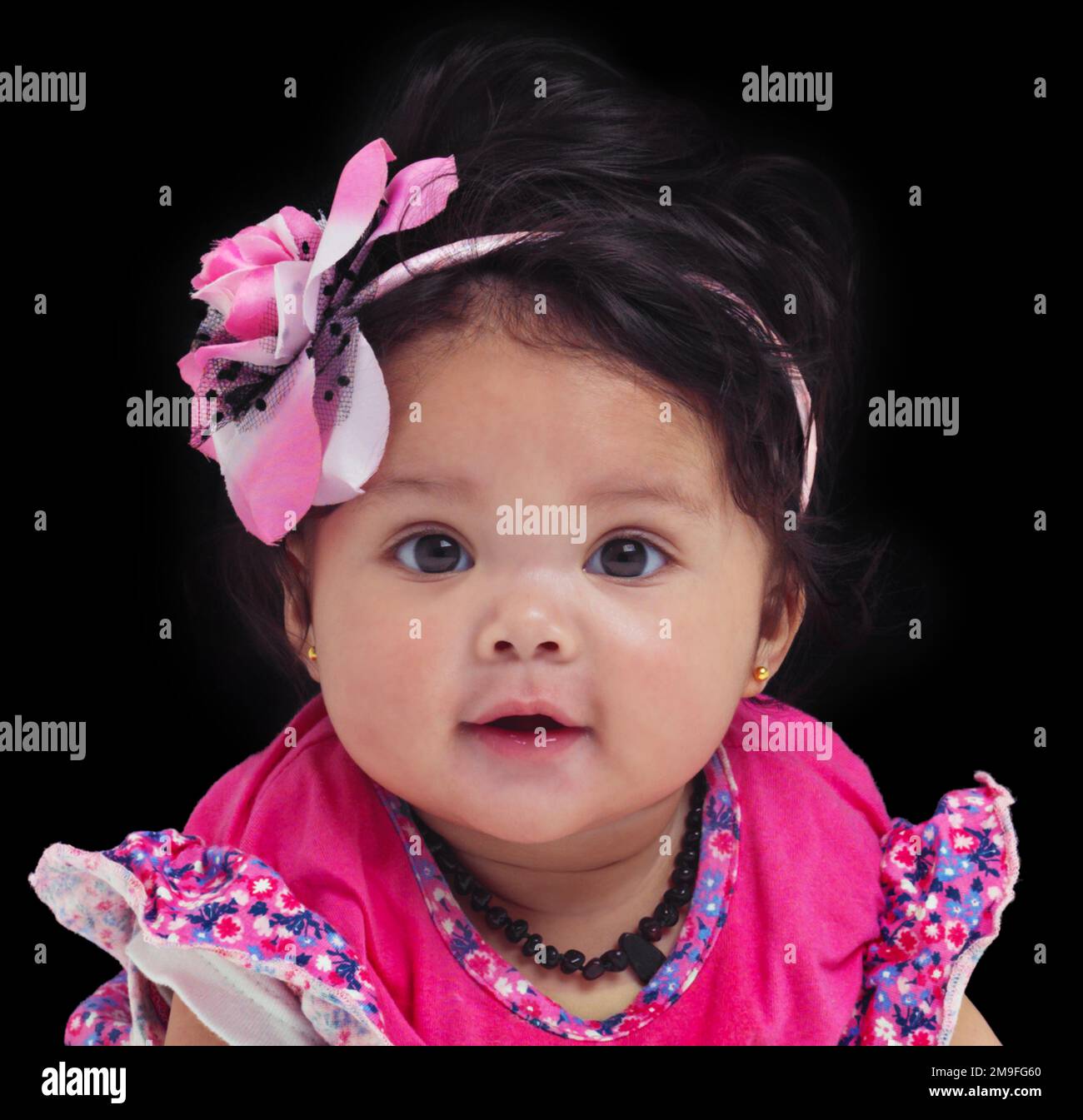Portrait, baby or girl with an innocent infant in studio on a black background in floral clothes. Kids, flower and development with a female child on Stock Photo