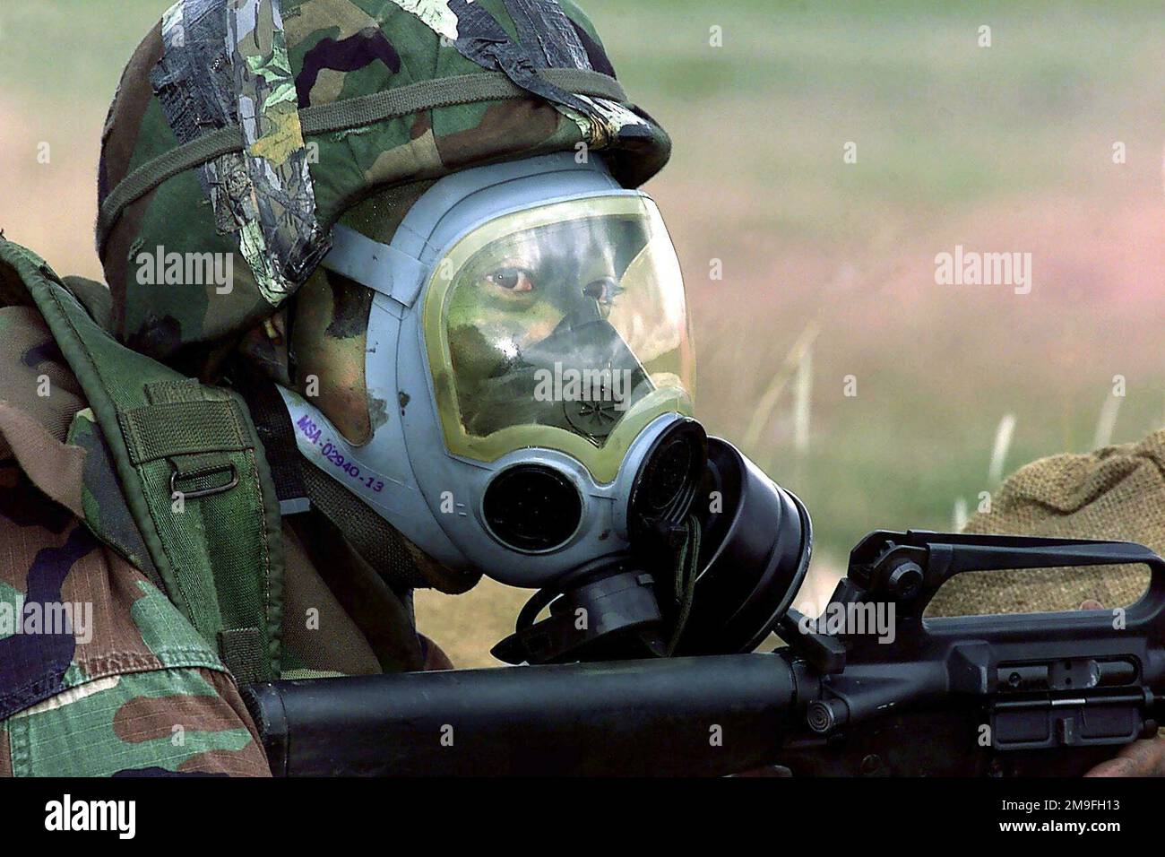 US Air Force Captain Steve Sugiyama, team leader and rifleman from the 11th Wing, dons gas mask during a simulated chemical attack in the Combat Weapons phase of DEFENDER CHALLENGE 2000 at Lackland Air Force Base, Texas. Defender Challenge is the annual Air Force wide competition sponsored by Air Force Security Forces. This competition showcases the talents and capabilities of 13 international Security Forces teams in 7 physical fitness, base defense, and policing skills over six days. Subject Operation/Series: DEFENDER CHALLENGE '00 Base: Lackland Air Force Base State: Texas (TX) Country: Uni Stock Photo