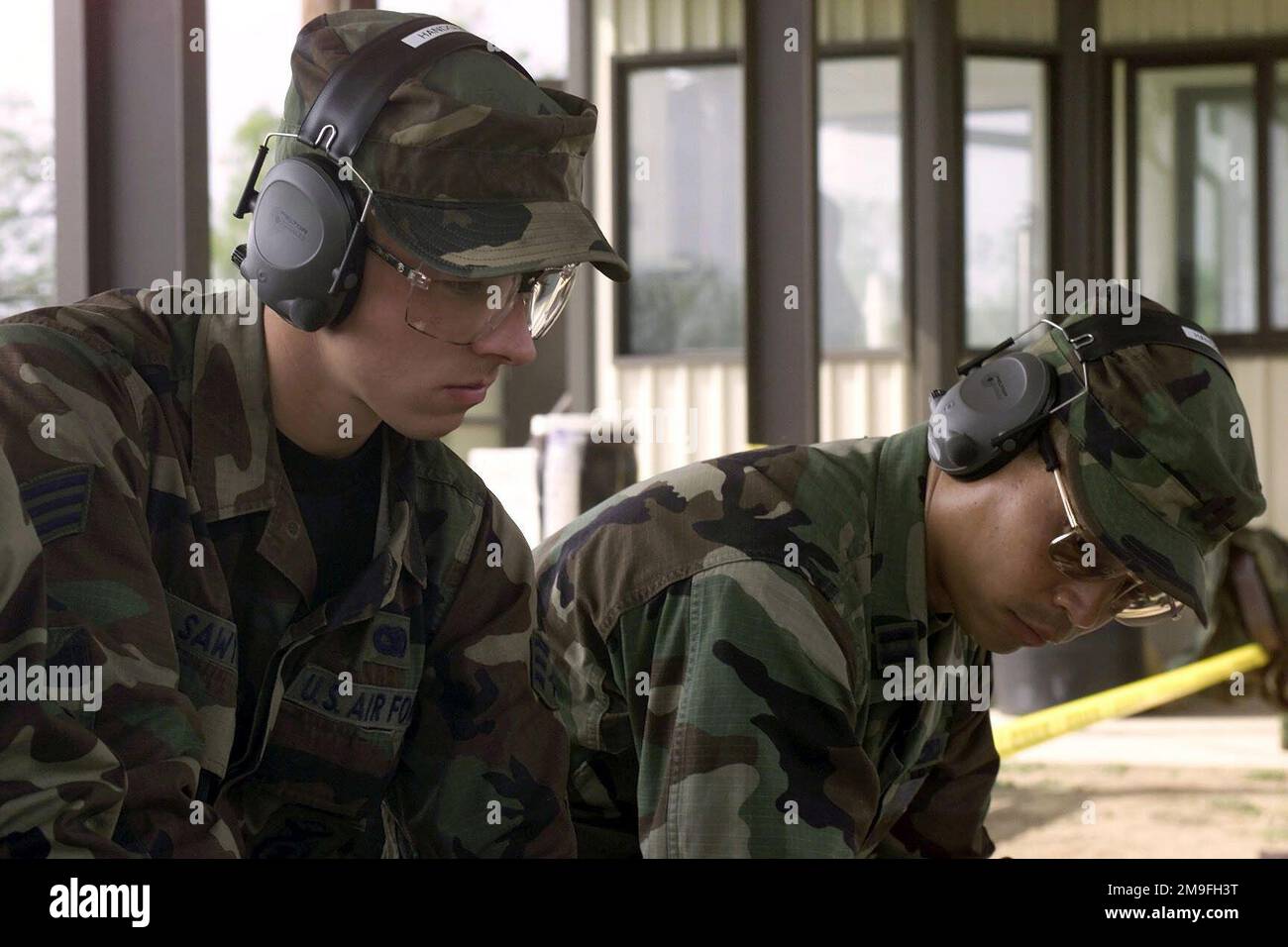 US Air Force SENIOR AIRMAN Eric Sawyer and US Air Force Captain Steve Sugiyama, from the 11th Wing, sit in deep concentration during the handgun portion of DEFENDER CHALLENGE 2000 at Lackland Air Force Base, Texas. Defender Challenge is the annual Air Force wide competition sponsored by Air Force Security Forces. This competition showcases the talents and capabilities of 13 international Security Forces teams in seven physical fitness, base defense, and policing skills over six days. Subject Operation/Series: DEFENDER CHALLENGE '00 Base: Lackland Air Force Base State: Texas (TX) Country: Unite Stock Photo